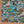Killer Acid Summer Slime swim trunks with a busy cartoon print of melting slime, smiley suns and skulls in teal, orange and yellow