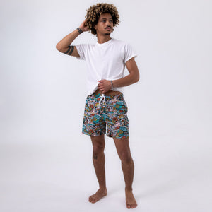 Killer Acid Summer Slime swim trunks with a busy cartoon print of melting slime, smiley suns and skulls in teal, orange and yellow