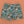 Killer Acid Summer Slime swim trunks with a busy cartoon print of melting slime, smiley suns and skulls in teal, orange and yellow